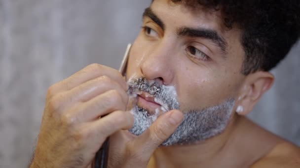 Όμορφος τύπος ξυρίζεται με ξυράφι στο σπίτι - 4K Οριζόντια βίντεο - Πλάνα, βίντεο
