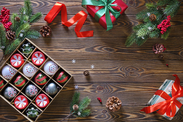 Ramas de árbol de Navidad, conjunto de bolas multicolores, cajas de regalo rojas y verdes con arcos en una mesa de madera de cerca - Foto, Imagen
