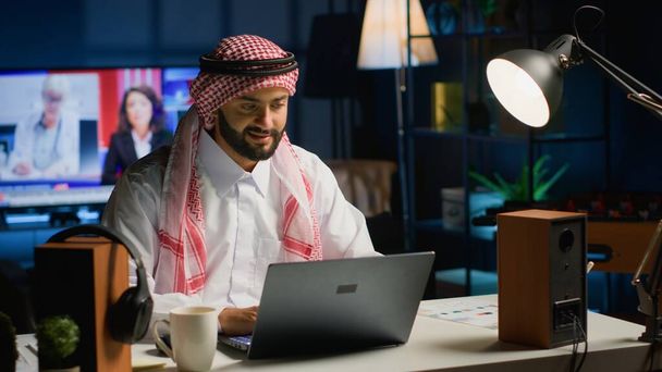 Arabski biznesmen piszący na laptopie, surfujący po sieci pijąc kawę. Bliskowschodni człowiek konwersacji przez e-mail, rozwiązywanie zadań klientów przy jednoczesnym korzystaniu z gorącego napoju - Zdjęcie, obraz