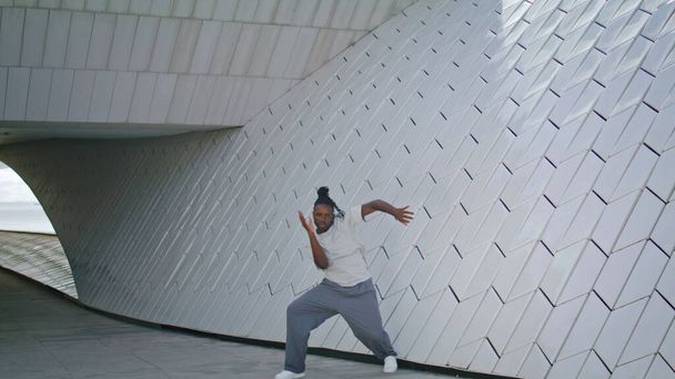 Kecses koreográfus tréning a városi építészetben. Kreatív ember tánc contemp és a modern balett mozog modern fal háttér. Érzéki afro-amerikai táncos drámai teljesítményt mutat  - Fotó, kép