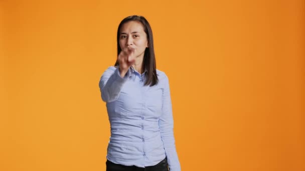 Modelo asiático apontando para a câmera em estúdio colorido, olhando para a lente com confiança. jovem filipino mulher aponta indicador dedo e de pé orgulhoso contra fundo laranja. - Filmagem, Vídeo