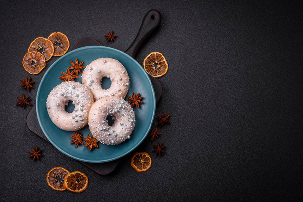 Heerlijke frisse donut van witte of beige kleur met zilveren kralen en crème op een donkere betonnen achtergrond - Foto, afbeelding