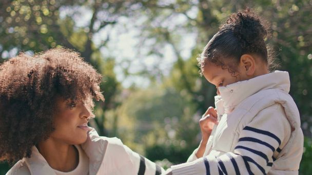African american woman daughter enjoying sunny weekend in beautiful green park close up. Curly young mother talking with adorable little girl outdoors. Smiling mom admiring cute child on nature. - Fotografie, Obrázek
