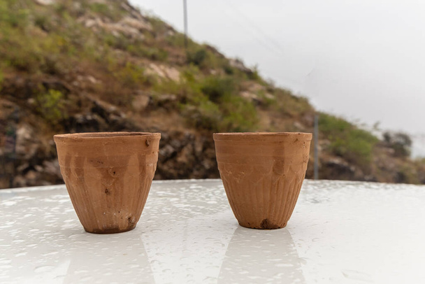 hete thee geserveerd in traditionele handleless aardewerk klei beker met wazig berglandschap - Foto, afbeelding