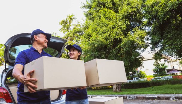 Delivery work home delivery service business : Retired senior male employee and female delivery driver stand together holding boxes waiting with smiles on their faces customers pick up their orders. - Photo, Image