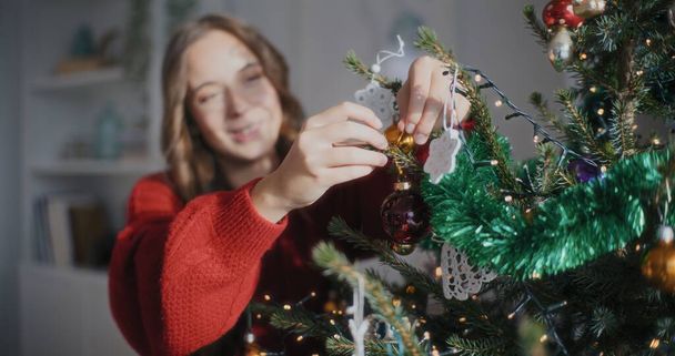 Vista de sorrindo alegre mulher preparando decorações de Natal Árvore de Natal durante feriados de Natal - Foto, Imagem