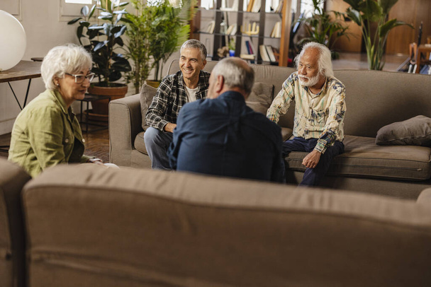 grupo de amigos mayores multirraciales hablan de su amistad en su sala de estar - Foto, imagen