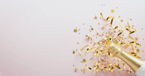 Gelukkig Nieuwjaar viering achtergrond concept. Champagne fles, gouden lint, sterren en kerstbal op pastelachtergrond. - Foto, afbeelding
