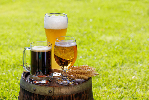 Variedad de vasos de cerveza en barrica de madera rústica. Soleado al aire libre con espacio de copia - Foto, imagen