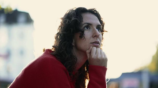 Задумчивая женщина, глядя на расстояние в городе Сансет, крупным планом лицо 20-ти лет человек с подбородком в глубокой интроспективной принятия решений, размышляя о жизни - Фото, изображение