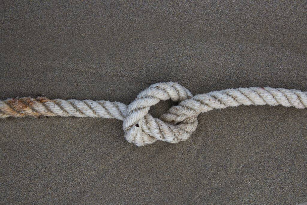 evocative image of a rope with a knot on the sandof a beach in Italy - Photo, Image