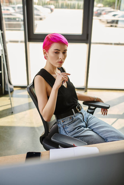 zamyšlená mladá růžová žena sedí s perem v rukou a tvrdě pracuje, obchodní koncept - Fotografie, Obrázek