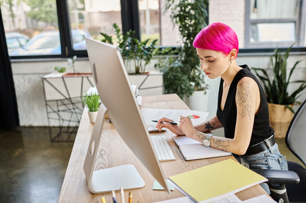 красивая задумчивая деловая женщина в городской повседневной одежде делает заметки во время работы за компьютером - Фото, изображение