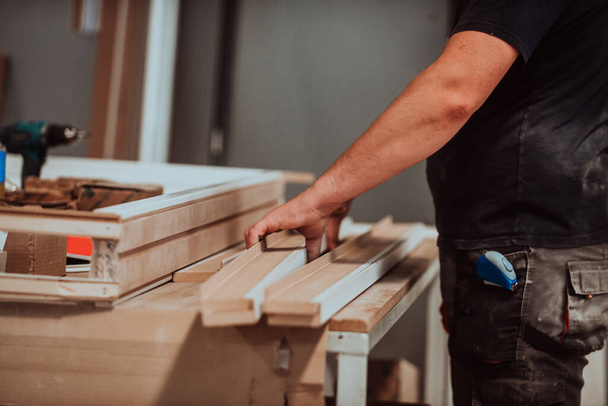 Un trabajador calificado en la industria de la carpintería utiliza hábilmente maquinaria moderna para procesar y preparar puertas de madera para el mercado, mostrando una mezcla perfecta de artesanía tradicional y corte - Foto, imagen