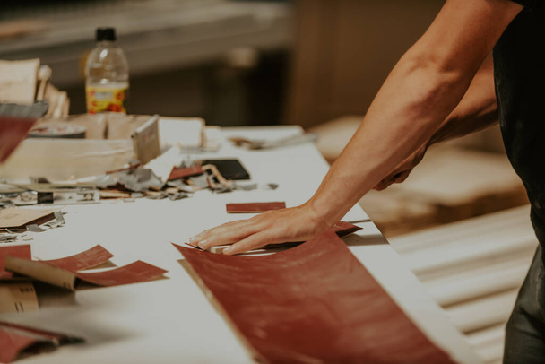 Um trabalhador diligente na indústria madeireira é visto meticulosamente cortando folhas de papel para o processo de polimento de madeira, mostrando precisão e atenção aos detalhes na preparação de materiais para - Foto, Imagem
