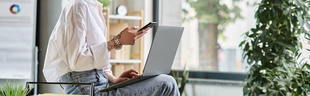 Ausgeschnittene Ansicht der jungen Geschäftsfrau, die mit Laptop auf den Knien sitzt und Telefon, Banner hält - Foto, Bild