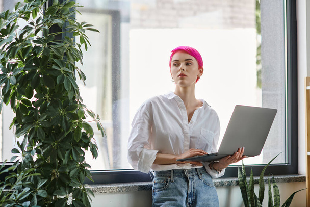 beautiful young female worker in white shirt and jeans holding laptop and looking away, business - Фото, зображення