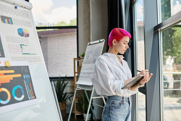 young attractive businesswoman with pink hair in white shirt taking her notes while at office - Foto, afbeelding