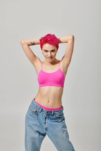 svůdný ženský model s růžovými vlasy a tetováním pózující a dívající se do kamery, módní koncept - Fotografie, Obrázek