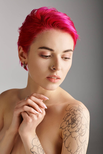 πορτρέτο της γοητευτικής και τόπλες νεαρή γυναίκα με γυμνούς ώμους και τατουάζ σε γκρι φόντο - Φωτογραφία, εικόνα