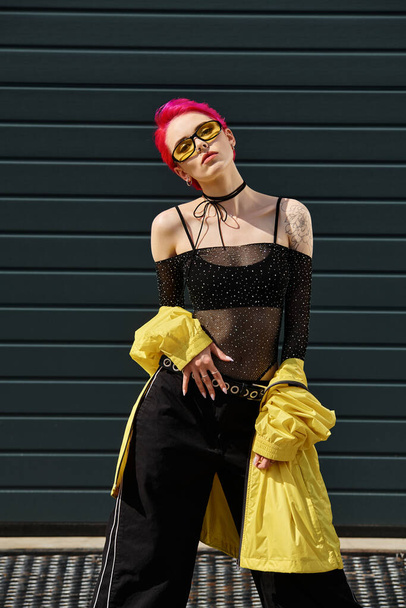 růžové vlasy mladá žena ve žlutých slunečních brýlích a stylové oblečení pózování na městské ulici venku - Fotografie, Obrázek