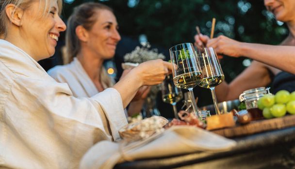 Друзья наслаждаются вином и едой на свежем воздухе возле финской мобильной сауны в сумерках - Фото, изображение