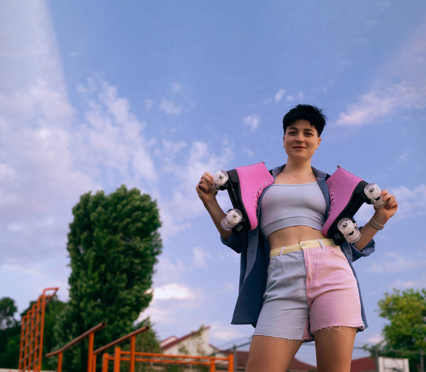 mulher atlética posando com um par de patins no ombro, sorrindo e olhando para longe, conceito de estilo de vida esportivo, espaço de cópia - Foto, Imagem