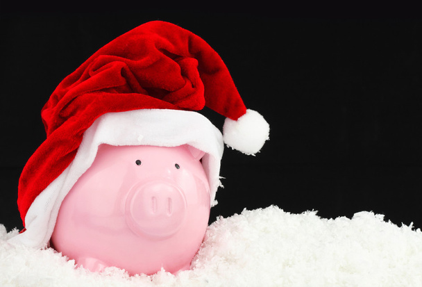 Santa claus piggy bank op sneeuw - Foto, afbeelding