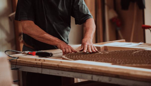 Een geschoolde arbeider in de houtbewerkingsindustrie maakt handig gebruik van moderne machines om houten deuren voor de markt te bewerken en te prepareren, met een naadloze mix van traditioneel vakmanschap en snijden. - Foto, afbeelding