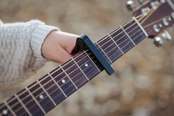Kytaristka, co drží capa u kytary. Hrát na kytaru pomocí capo (hudební zařízení) - Fotografie, Obrázek