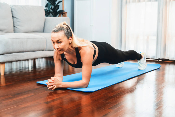 Mujer mayor atlética y deportiva planking en la alfombra de ejercicio de fitness en el ejercicio en casa como concepto de estilo de vida corporal en forma saludable después de la jubilación. Clout. - Foto, imagen