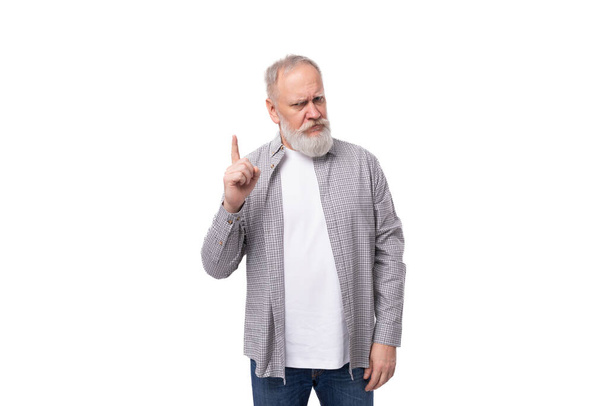 schöner grauhaariger älterer Mann im Hemd zeigt seinen Zeigefinger nach oben auf weißem Hintergrund mit Kopierraum. - Foto, Bild