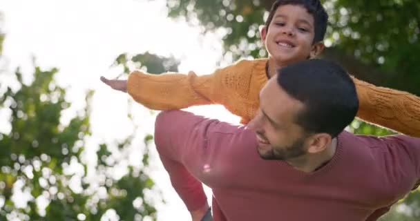 Father, son and piggyback, bonding outdoor and happy with quality time together, playful and fun in garden. Man, boy child and swinging in park, relax in nature with summer and family, love and care. - Footage, Video