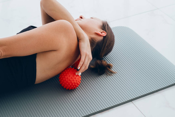 Жінка лежить на маленьких м'ячах для усунення болю в спині, масажу жорстких м'язів і грудного болю в спині, виконує вправи для полегшення болю в хребті. Розслаблення і розтягування м'язів - Фото, зображення
