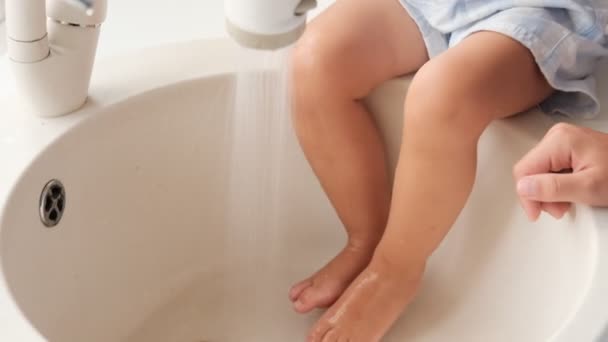 Kid, child girl washes feet in kitchen sink under running water. High quality FullHD footage - Footage, Video