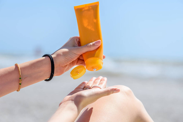 Une femme tenant des bouteilles de crème solaire dans ses mains. Gros plan. - Photo, image