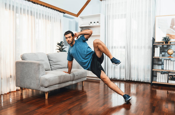 Corpo atlético e homem esportivo ativo usando móveis para o exercício de ganho muscular eficaz alvo em casa alegre exercício como conceito de corpo saudável ajuste estilo de vida de treino em casa. - Foto, Imagem