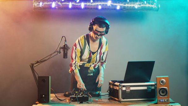 DJ esiintyjä luoda tekno musiikkia ohjauspainikkeilla, yllään hullu meikki ja sekoittamalla audio stereolaitteet. Taiteilija soittaa diskoa levysoittimissa yökerhon juhlissa. Kolmijalka laukaus. - Valokuva, kuva