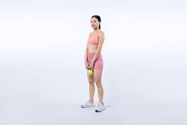 Silná energická žena dělá kettlebell zvedání hmotnosti cvičení na izolovaném pozadí. Mladý atletický asijské žena síla a vytrvalost školení jako tělo cvičení rutina. - Fotografie, Obrázek