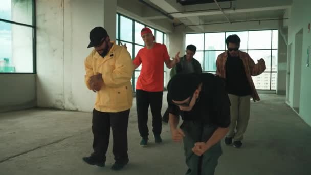 A multikulturális táncos utcai táncot gyakorol és hip-hop zenére váltott. A profi hipszter csoport freestyle zenére táncol az égre néző épületekben. Szabadtéri sport 2024. hiphop. - Felvétel, videó