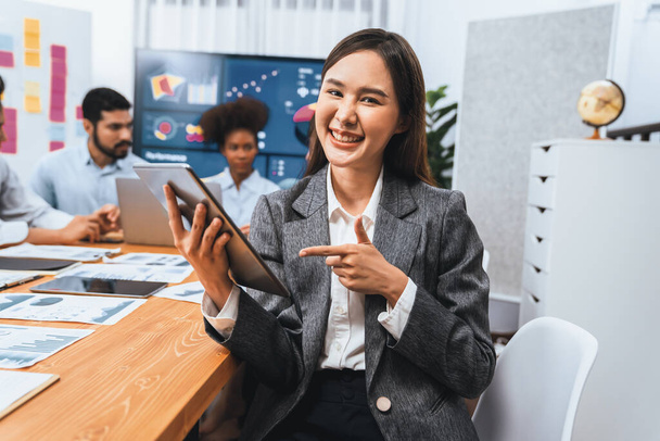 Portrait of happy young asian businesswoman with group of office worker on meeting with screen display business dashboard in background. Confident office lady at team meeting. Concord - Photo, Image