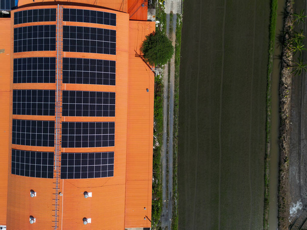 Fabrika deposunun çatısındaki güneş enerjisi sisteminin üst hava görüntüsü. Enerji ve karbon ayak izini azaltmak için fotovoltaik yenilenebilir enerji. Temiz enerji. Yapımda güneş paneli ve yapı. - Fotoğraf, Görsel