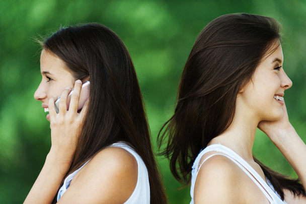 Duas mulheres perfil falar telefone
 - Foto, Imagem