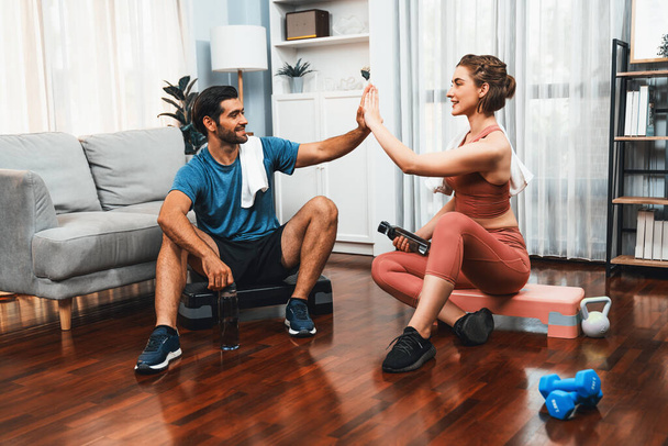Athletic body and sporty young couple or workout buddy in sportswear warmup or resting after finishing in home workout exercise at gaiety home exercise and healthy lifestyle concept. - Foto, imagen