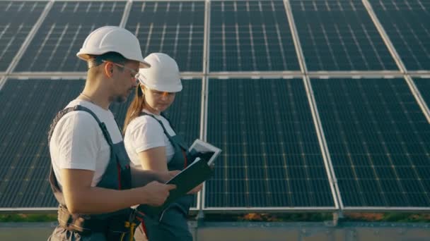 The chief engineer and specialist study the report on the results of the solar power plant while walking around the farm. Business team. Clean energy. Industry. High-quality 4K shooting - Footage, Video