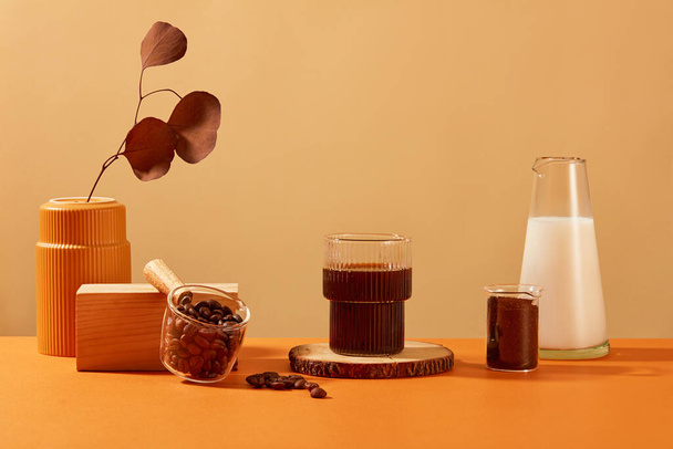 Una taza de café negro se muestra en un tronco, las hojas de otoño se colocan en un jarrón de cerámica. Espacio de exhibición de café para publicidad. El café contiene muchos antioxidantes que son beneficiosos para la piel. - Foto, Imagen
