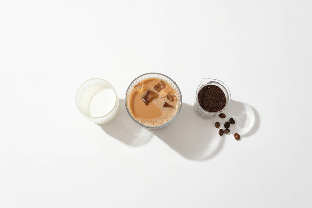 Bir fincan süt, bir fincan sütlü kahve ve beyaz zemin üzerinde kahve tozu olan bir beher. Kahvenin içindeki kafein beyne ve merkezi sinir sistemine birçok sağlık yararı getirir.. - Fotoğraf, Görsel