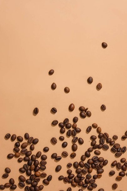 Granos de café esparcidos sobre un fondo rosa. Espacio ideal para mostrar productos que contienen extracto de café. Sea creativo con granos de café para la publicidad. - Foto, Imagen