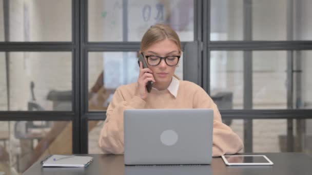 Mladá žena mluví po telefonu v práci - Záběry, video