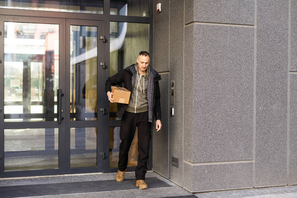 Человек, стоящий у тёмной входной двери на улице. Пустое место для логотипа или дизайна - Фото, изображение